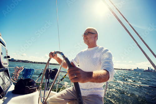 senior man at helm on boat or yacht sailing in sea photo