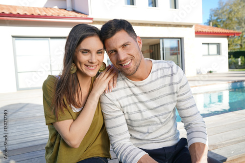 Obraz na plátně Cheerful young couple sitting in front of new home