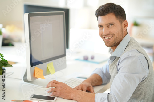 Handsome businessman working on desktop computer in office