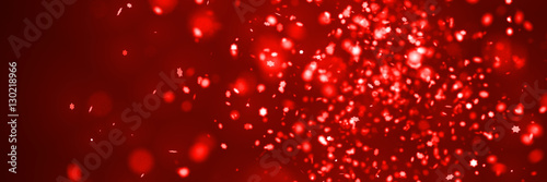 glitter banner: festive twinkling star-shaped red glitter with bokeh effect in front of a dark red background