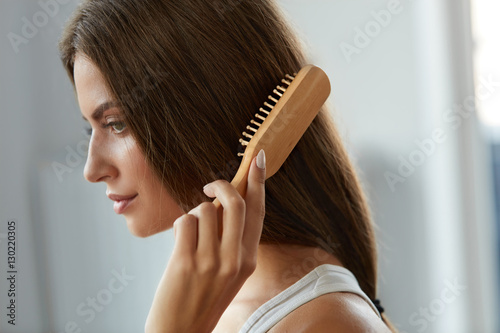 Woman Brushing Beautiful Healthy Long Hair With Brush Portrait photo