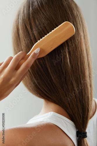 Back View Of Woman With Healthy Long Hair Brushing It With Brush