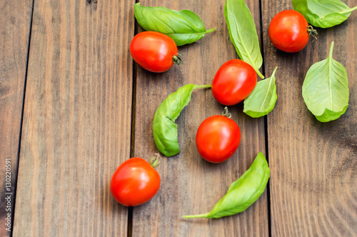 Tomatoes with basil leaves on a wooden background. Top view