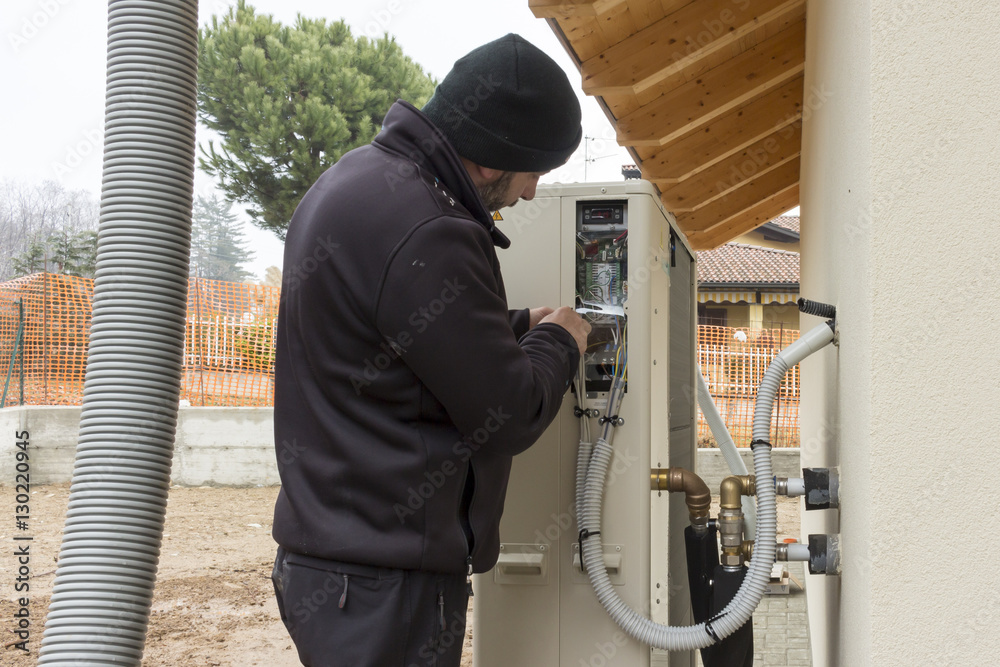 plumber at work installing a heat pump for heating