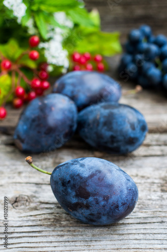Plums with grapes on a wooden background. Top view. Close-up