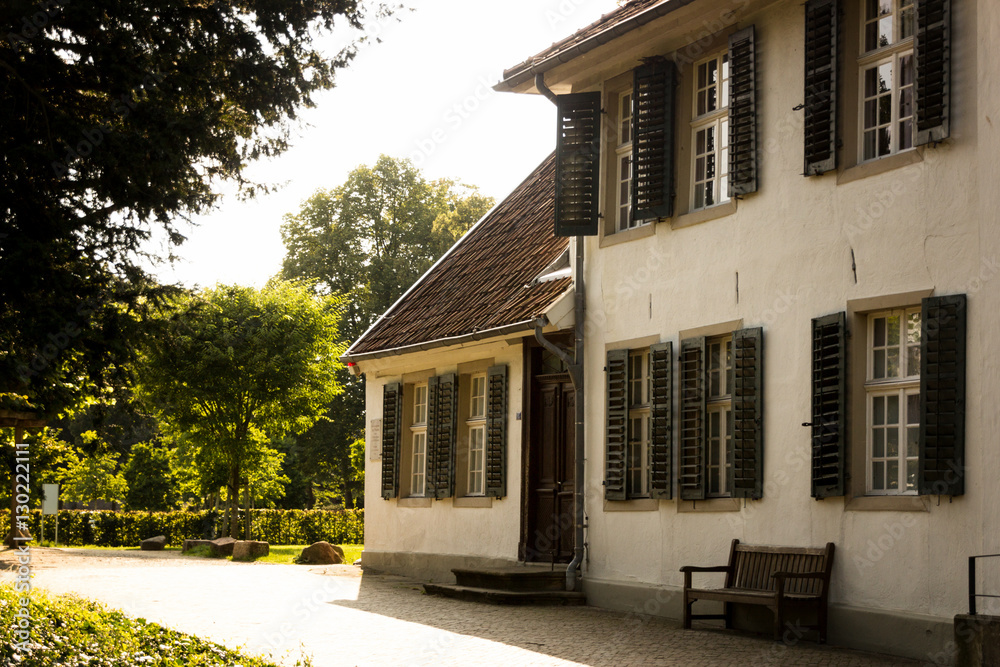 Fototapeta premium Altes Haus mit Fensterläden in einem Park im Münsterland