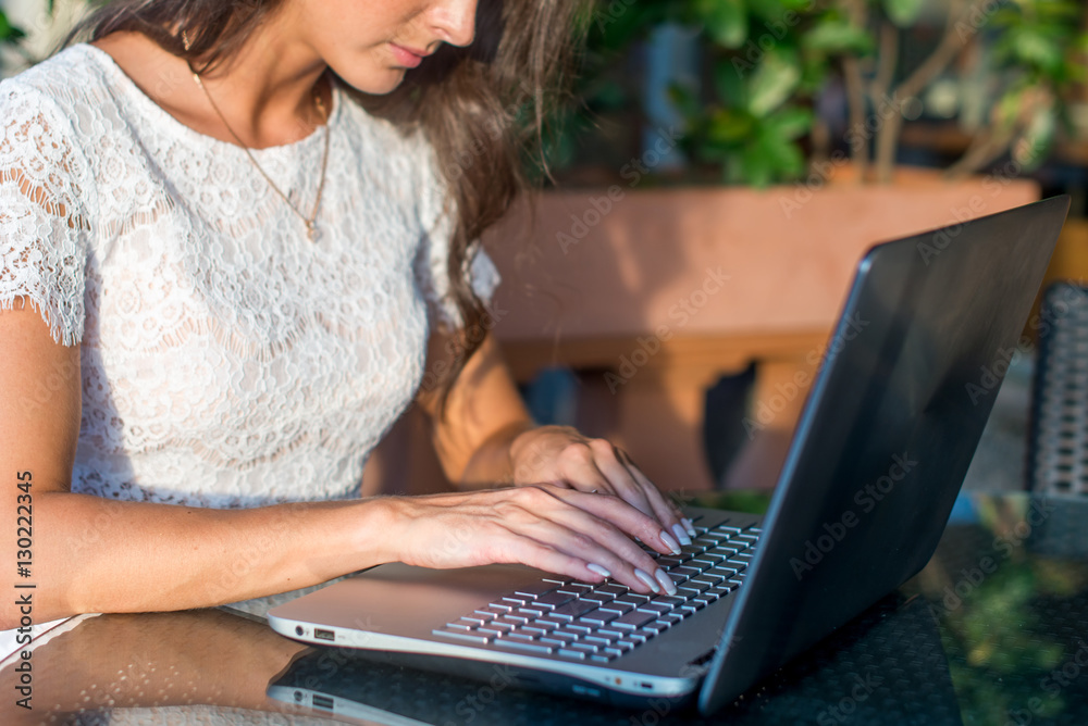 Close-up view of female hands typing on keyboard. Businesswoman working her laptop computer at outdoor cafe. Close-up view of female hands typing on keyboard. Businesswoman working her laptop computer at outdoor cafe.