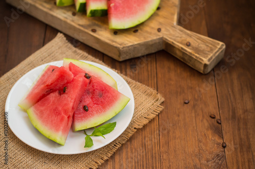 Watermelon sliced slices with a sprig of mint on wooden background. Top view