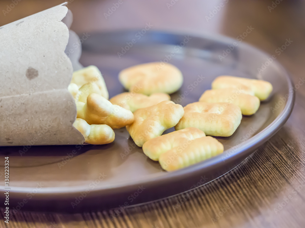Closeup of alphabet biscuits on brown ceramic plate Closeup of alphabet biscuits on brown ceramic plate