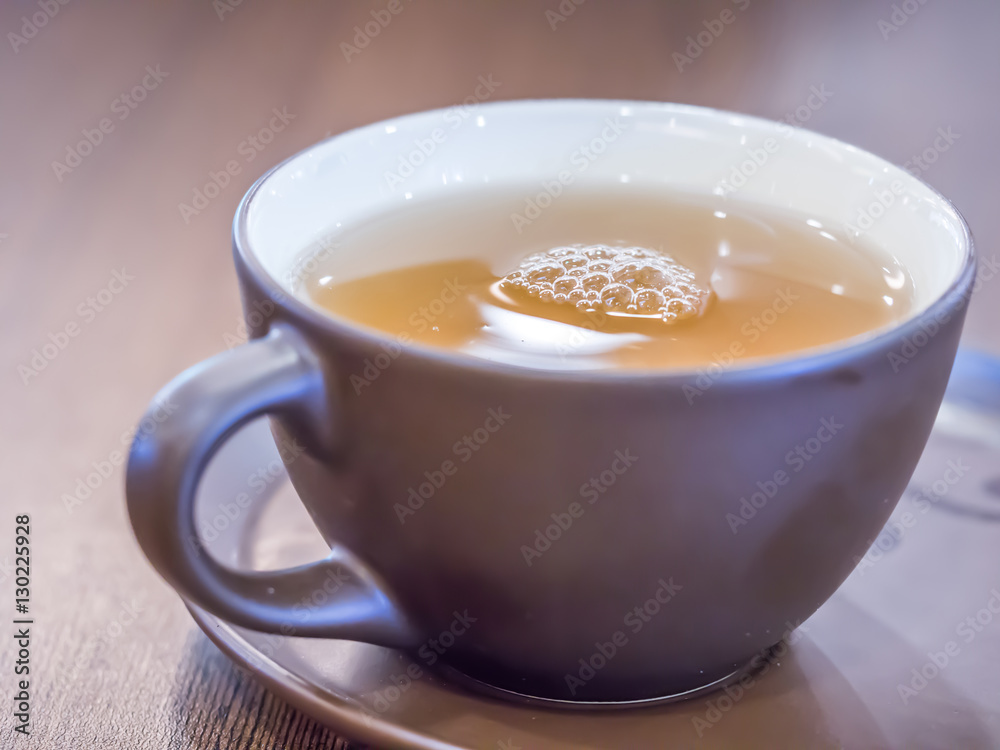Closeup of brown ceramic cup of tea with blurry wooden table Closeup of brown ceramic cup of tea with blurry wooden table