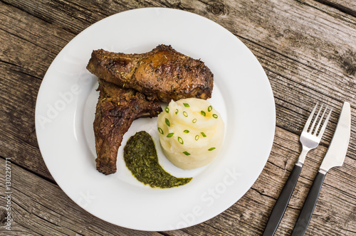 Pork steak on the bone grilled with mashed potatoes and spinach  herbs sauce. Wooden background. Close-up. Top view
