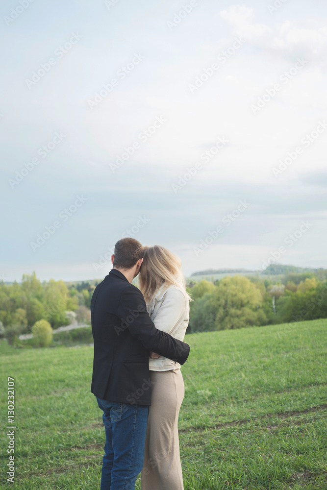 Couple. Couple standing back to camera. Couple in a field in spring. Boy and girl posing in the field. Love story. Couple. Couple standing back to camera. Couple in a field in spring. Boy and girl posing in the field. Love story.