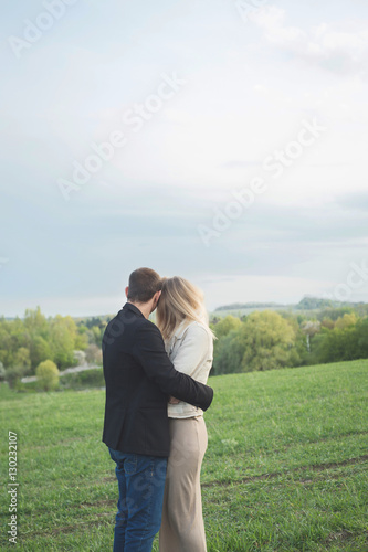 Couple. Couple standing back to camera. Couple in a field in spring. Boy and girl posing in the field. Love story. © avdeyukphoto