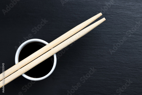 Soy sauce in small white bowl with chopsticks.