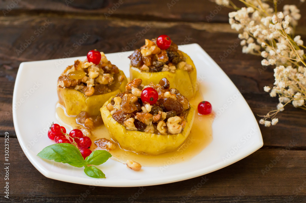 Baked apples with raisins, walnuts and honey for dessert. Wooden rustic background. Close-up Baked apples with raisins, walnuts and honey for dessert. Wooden rustic background. Close-up