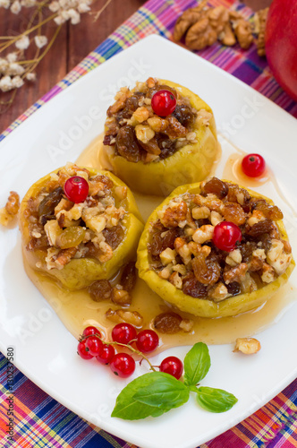 Baked apples with raisins, walnuts and honey for dessert. Wooden rustic background. Close-up. Top view