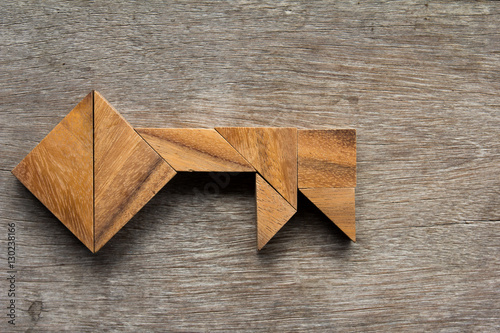 Wooden tangram as key shape on old wood background