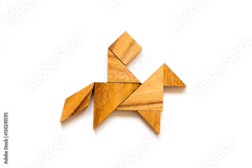 Wooden tangram as man riding horse shape on white background