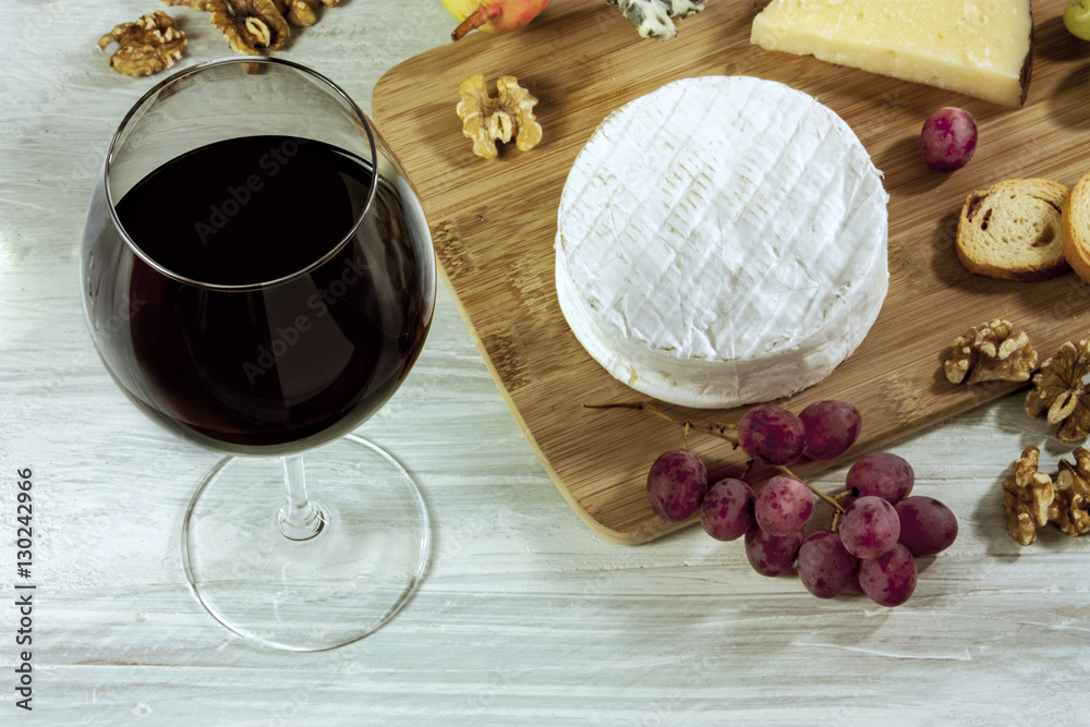 Wine, cheese, grapes and nuts on wooden board