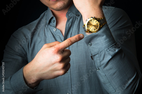 Businessman showing time on his gold watch
