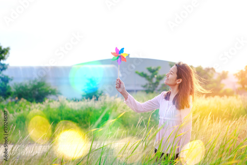 Beautiful girl holding wind toy or wind turbine or pinwheel and wool hat at meadow on winter season in morning.