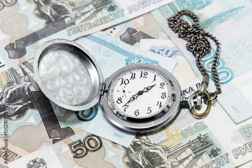 Time is money. The clock on the background of Russian money