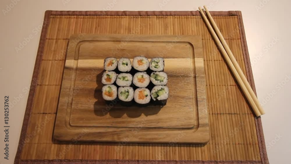 Man places the board with sushi on the table. The waiter is lodging the sushi Man places the board with sushi on the table. The waiter is lodging the sushi