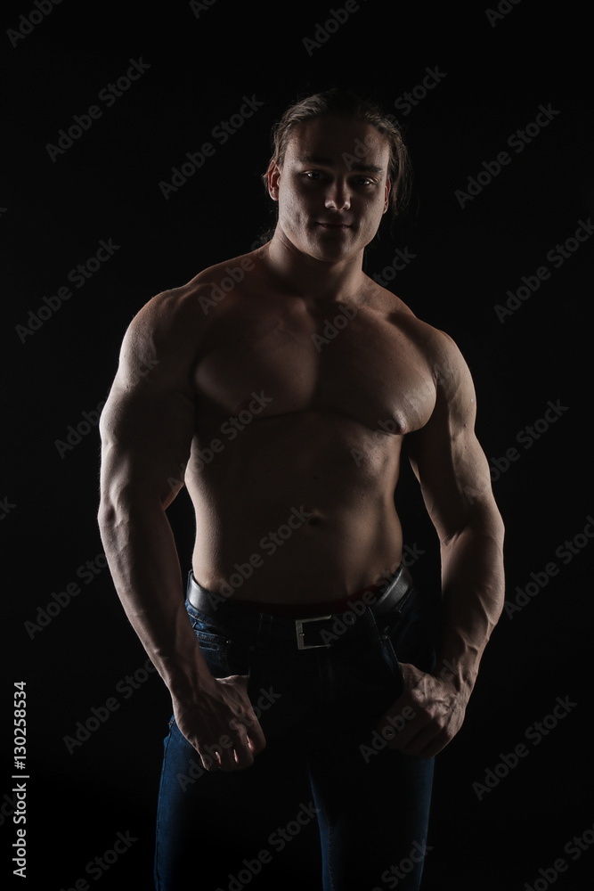 naked torso male bodybuilder athlete with long blond hair in studio on a black background Stock