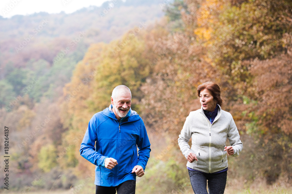 Naklejka premium Beautiful senior couple running outside in sunny autumn nature