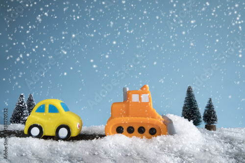 Snow plow. Toy car in a little winter landscape. Concept of road cleaning and road safety.