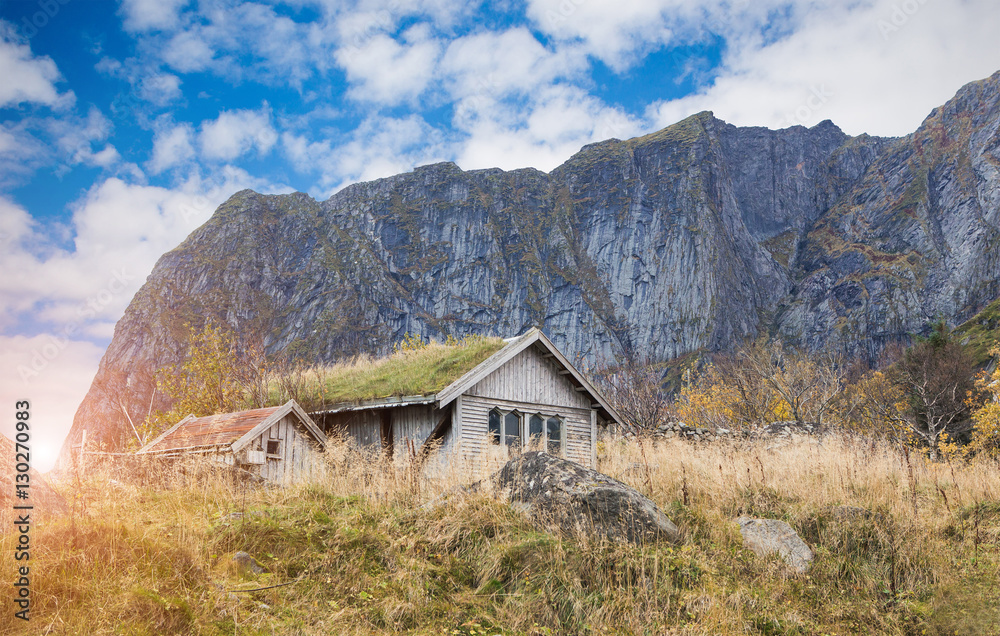 Old wooden house in the mountains. On the roof of the house growing green grass. Scandinavia.