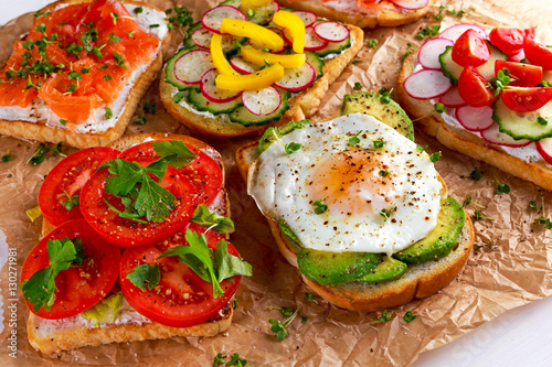 Variety of vegetarian toast sandwiches with salmon, raddish, tomatoes, cucumber, avocado,fried egg and sweet pepper