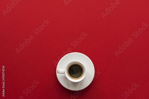  little white cup of aromatic black espresso on red vinous background 