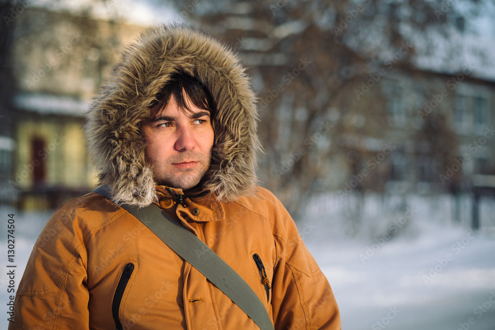 Portrait of the charming man who is smiling and talking on the phone in the winter cold day at sunset, dawn. Portrait of the charming man who is smiling and talking on the phone in the winter cold day at sunset, dawn.
