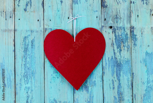 Large red heart hanging on teal blue wood background