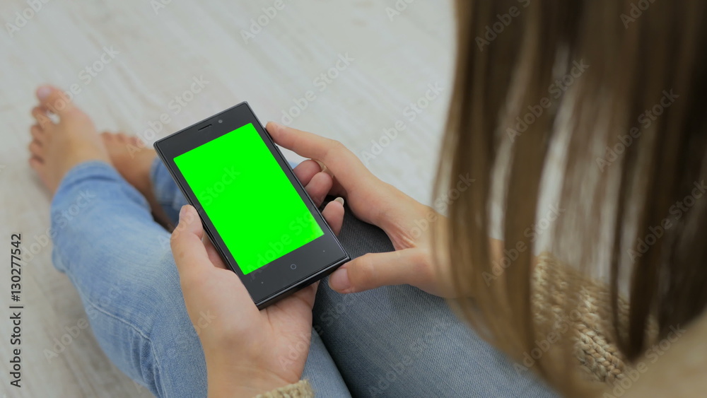 Woman looking at smartphone with green screen. Close up shot of woman's hands with mobile Woman looking at smartphone with green screen. Close up shot of woman's hands with mobile
