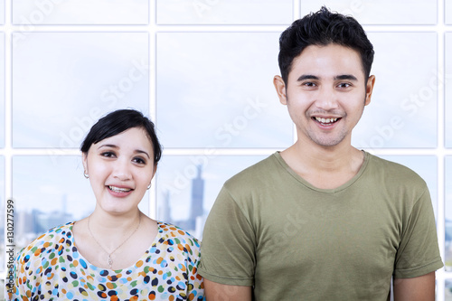 Cheerful couple looking at camera in apartment