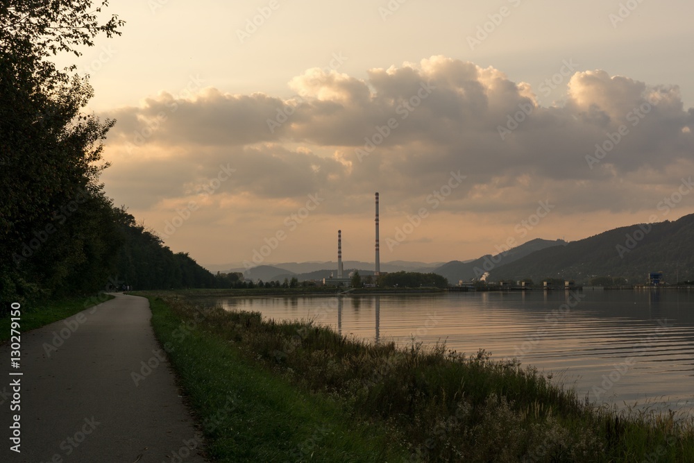 Chimneys of town and clouds with reflections in water reservoir on river Vah. Slovakia