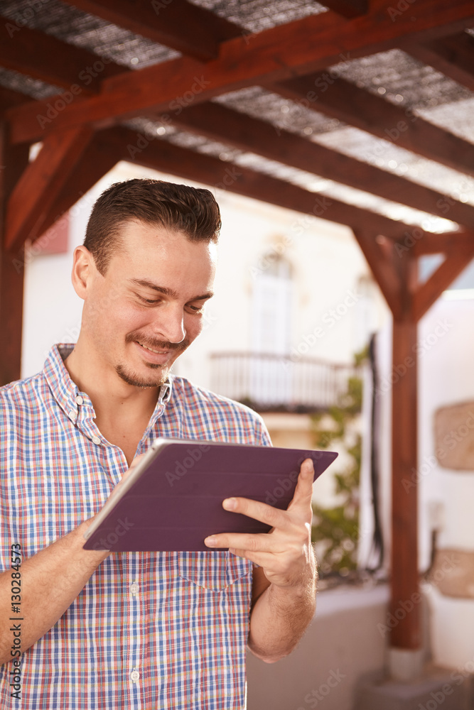 Cool dark haired guy smiling at tablet