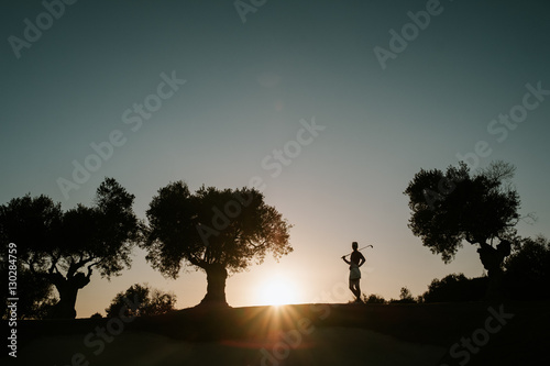 Golferin steht im Sonnenuntergang