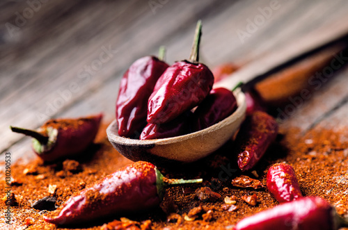 Red chilli peppers, spicy on a wooden spoon. Vegetable on a dark, wooden table. Concept of hot food.  photo