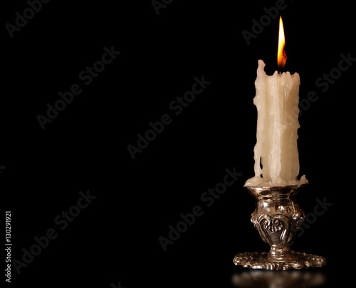 burning old candle vintage Silver bronze candlestick. Isolated Black Background.