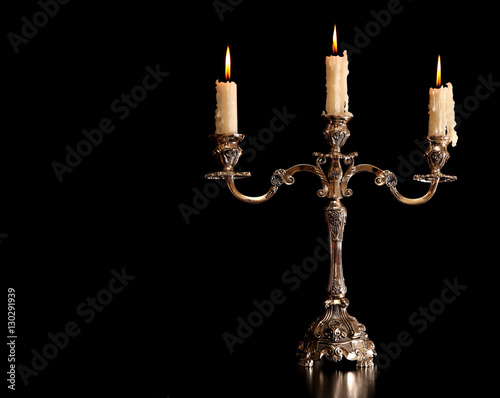 burning old candle vintage Silver bronze candlestick. Isolated Black Background. photo