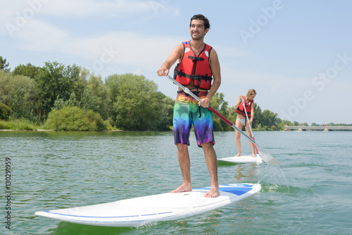 couple paddle boarding on lake photo