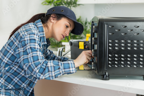 a woman fixing a small oven photo