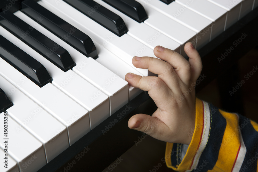 Obraz premium the hand of a little boy on the piano keys