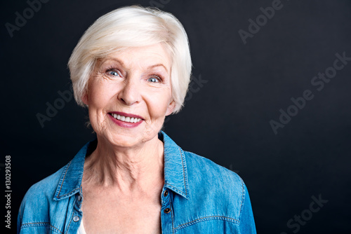 Fotografie Cheerful elderly woman standign on black background