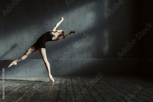 Papier peint Skillful young ballet dancer acting in the black colored room