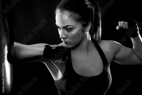 Studio shot of female boxer punching a boxing bag with elbow, Black and white.