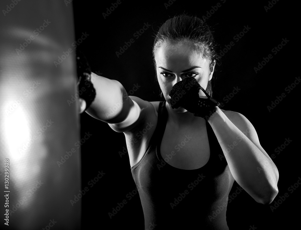 Studio shot of female boxer punching a boxing bag, Black and white.